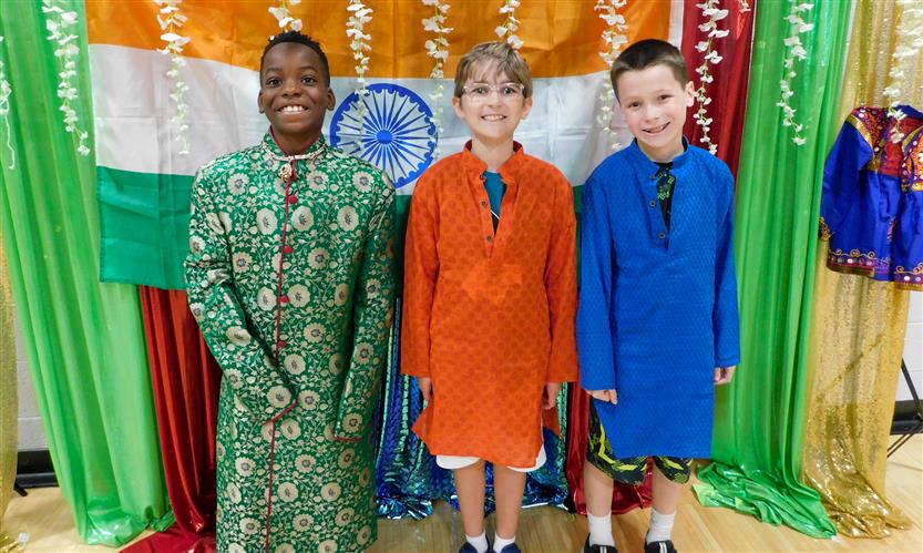 A group of students stands in front of a backdrop and smiles